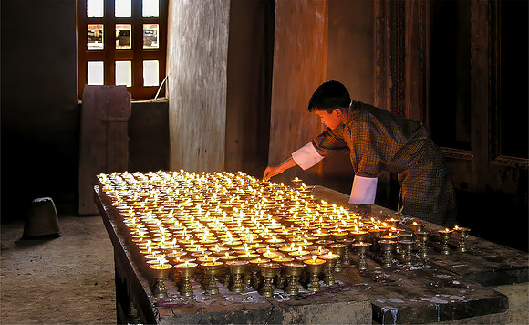Novice tending butter lamps in Gangtey Gompa, Phobjikha Valley, Bhutan 2005